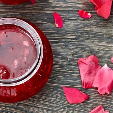 Rose petal jam in jar and fresh red petals.